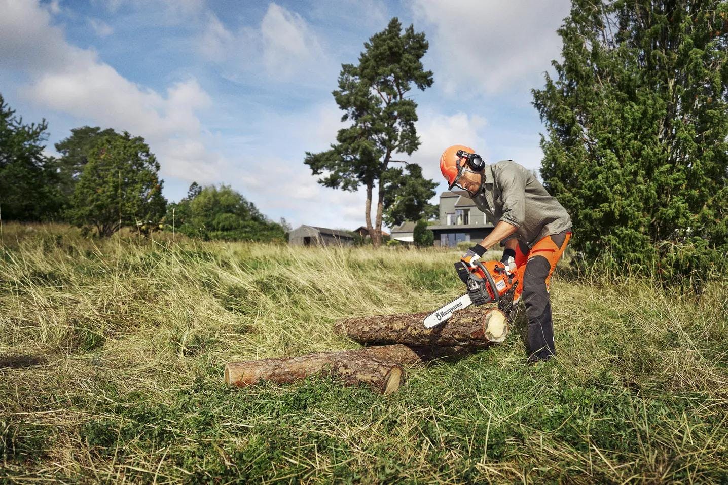 man using chainsaw in large backyard