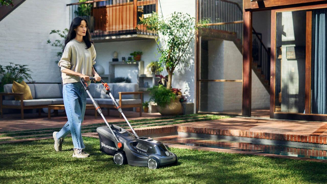 woman with aspire lawn mower in backyard